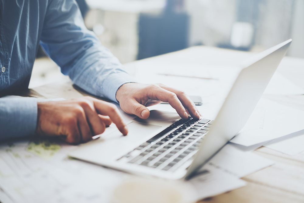 Closeup of man on laptop working on website