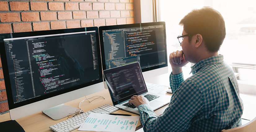 Man working on computer, multiple monitors, website backend, coding cover