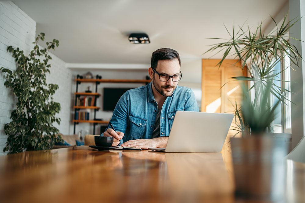 Man working on laptop at table, working on website