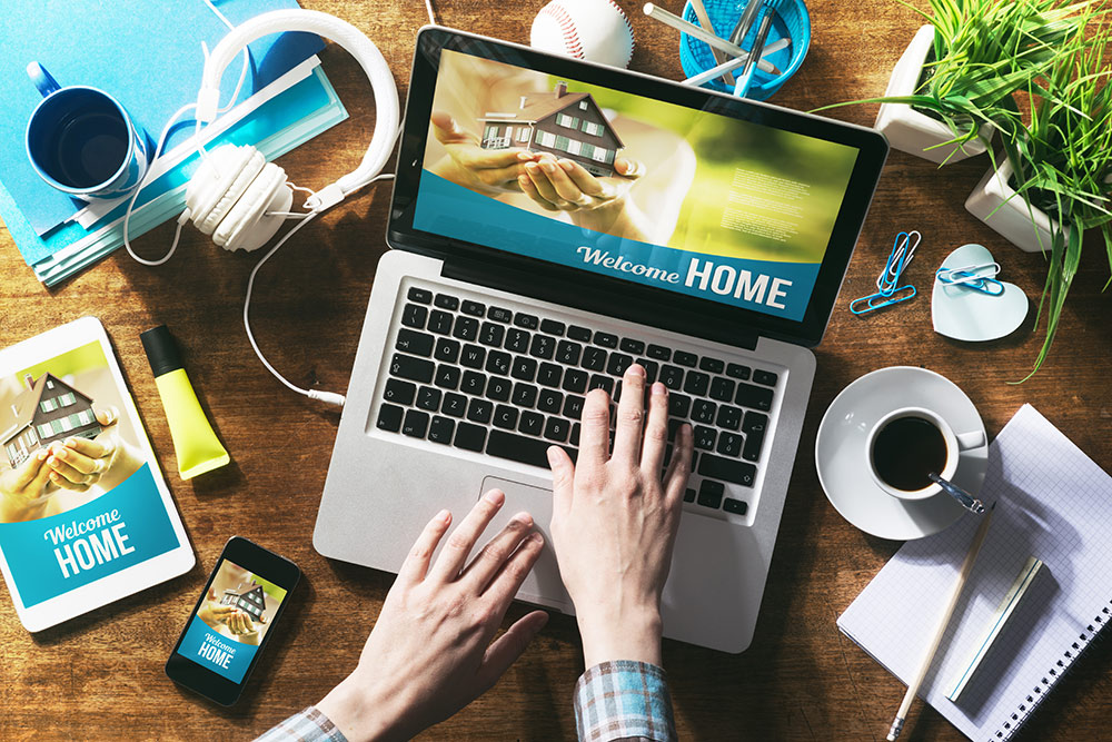 Person on computer looking at website for new home, also showing website on tablet and smartphone