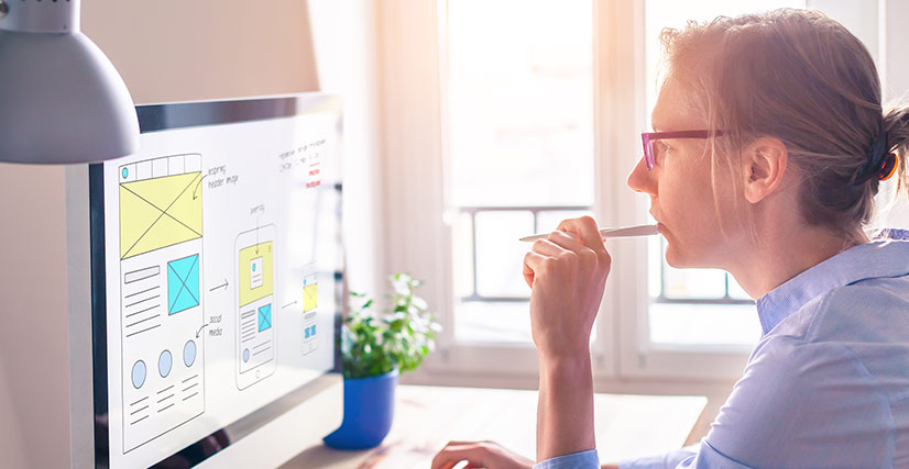 Woman looking at computer laying out a website design