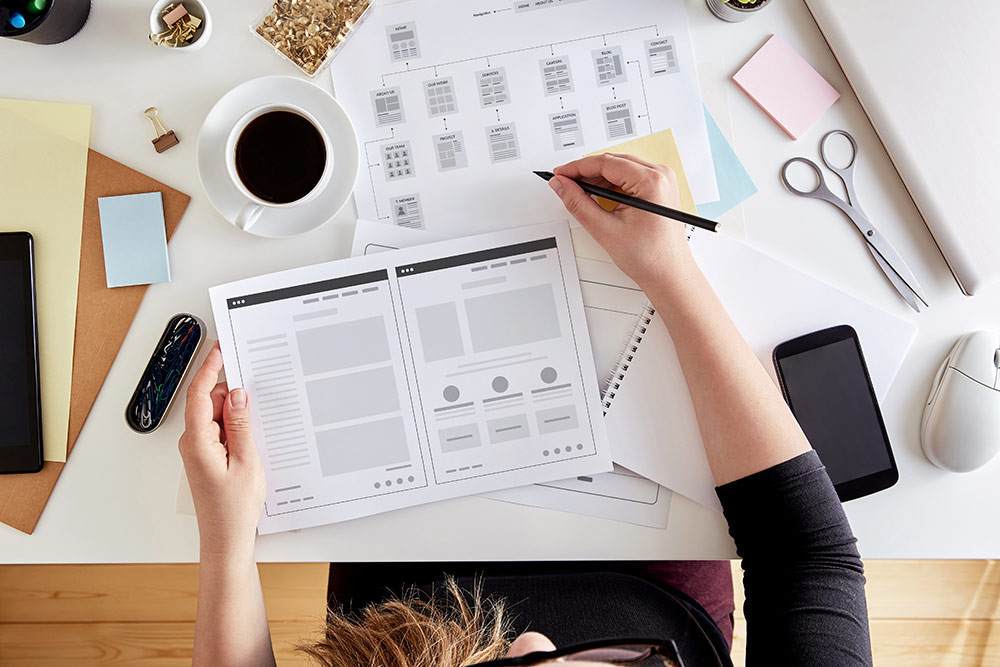 Person sitting at desk working on web design wireframe